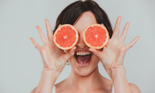 Frau hält zwei Grapefruithälften vor ihre Augen - Grapefruits führen zu zahlreichen Wechselwirkungen mit Medikamenten 